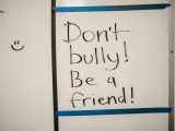 Message against bullying written on a whiteboard, promoting friendship.